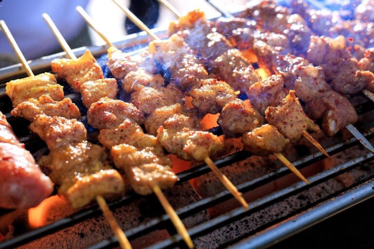 Home BBQ pakket voor 20 personen met vlees, vis, salades en bijgerechten op tafel klaar voor servering